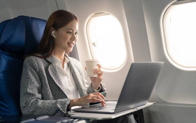Frau mit Laptop im Flugzeug
