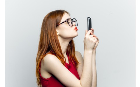 Frau mit Smartphone macht Kussmund