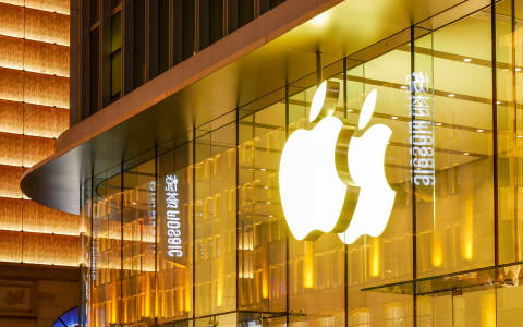 Leuchtendes Apple-Logo an einer gläsernen Gebäudefassade